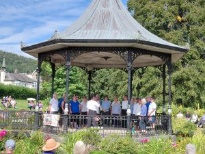 Grange over Sands bandstand on a sunny summer day with The Growing Singers performing for a gathered crowd