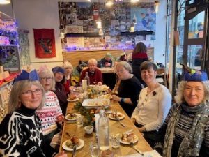 Diners enjoying a tapas Christmas meal together, a few are wearing colourful paper hats