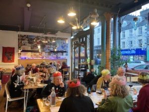 Diners enjoying a tapas Christmas meal together, a few are wearing colourful paper hats