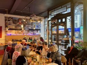 Diners enjoying a tapas Christmas meal together, a few are wearing colourful paper hats
