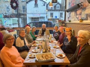 Diners enjoying a tapas Christmas meal together, a few are wearing colourful paper hats